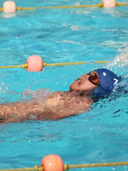 A swimmer perfecting their backstroke technique under the sun at our outdoor pool.