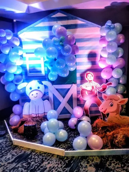A dedicated photo corner at the Cocomelon party, featuring a barnyard theme with character cutouts and balloon decorations.