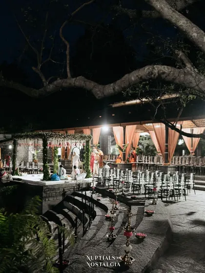 The Pond Pavilion at night, set up for a ceremony with elegant lighting and seating on the stone steps.