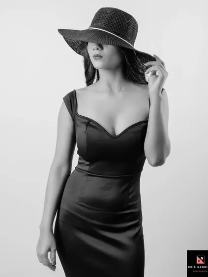 Another take from the 'Opulence' series, this black and white shot shows the model adjusting her hat. The monochrome tones emphasize the classic, elegant feel of the portrait.