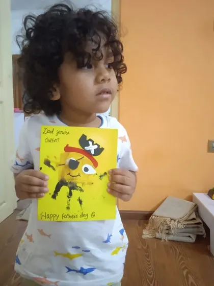 A child proudly displays the Father's Day card he made. This footprint pirate art is a perfect example of how we combine process art with creating a heartfelt gift.