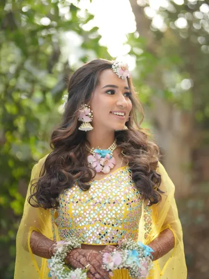A beautiful, happy bride at her Haldi. Her pastel floral jewellery set was custom-made to complement the colours in her mirror-work lehenga.