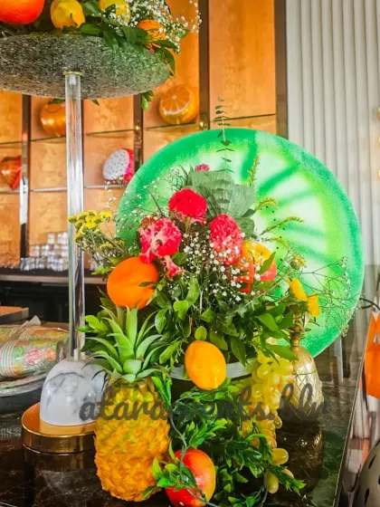 Every corner is thoughtfully decorated. This centerpiece combines fresh flowers with a variety of fruits and a large watermelon-slice prop, tying the theme together across the venue.