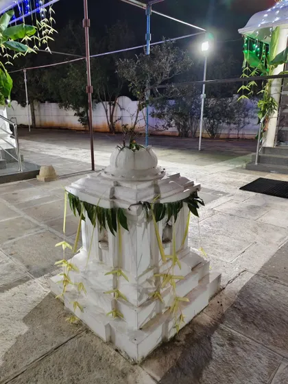 A Tulasi katte (sacred basil platform) at the temple, simply decorated with mango leaves and woven leaf hangings.
