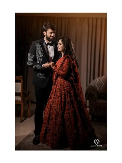 A classic couple portrait from their reception. The groom's formal suit and the bride's stunning red gown create a look of timeless elegance as they hold hands, ready to start their new chapter.