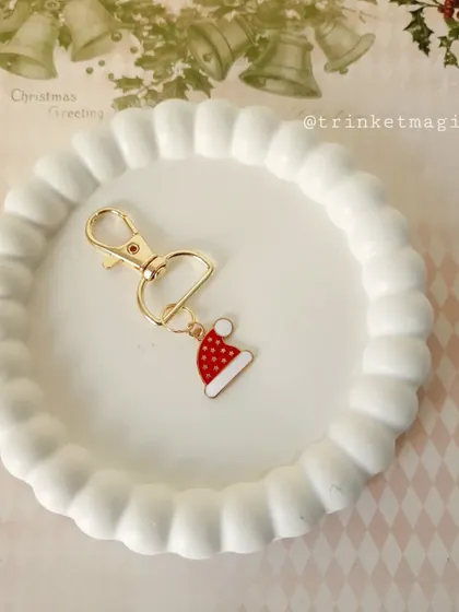 A cute Santa hat charm, perfect for a subtle nod to the holiday season. You can clip it onto any zipper or bag.