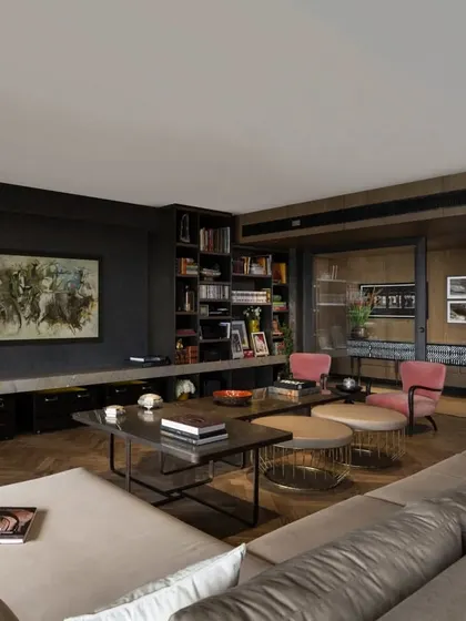 This angle shows the flow from the living room towards the entrance corridor in the Caitriona apartment. The herringbone wood floor defines the seating area, while the mix of contemporary furniture and a curated bookshelf wall creates a space that is both stylish and lived-in.