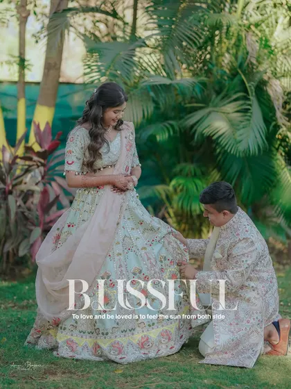 A chivalrous moment in a beautiful garden setting. The groom helps the bride with her shoe, a sweet and candid capture from their engagement shoot.