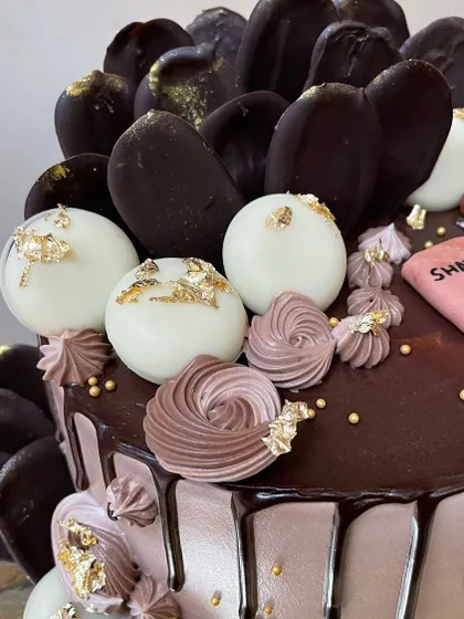 A close-up of the chocolate hearts, white chocolate spheres, and meringue kisses on the book lover's cake.