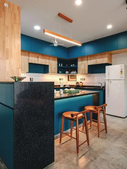 The kitchen is the heart of this home, featuring bold teal cabinetry, natural rubberwood accents, and a spacious breakfast counter for casual meals.