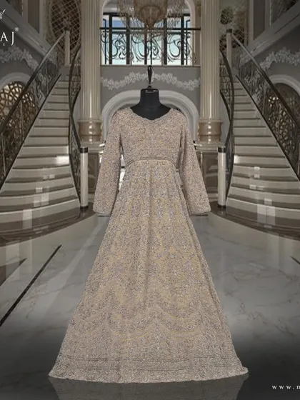 A studio shot of the stunning light beige tail gown, with intricate flowy embellishments that add a touch of richness and royalty.