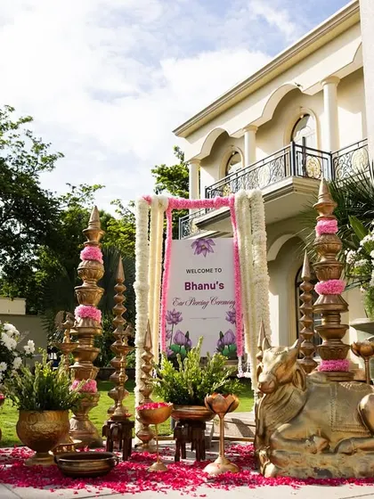 A detailed view of the beautiful welcome decor for Bhanu's ear piercing ceremony, featuring brass lamps, floral arrangements, and a personalized sign.