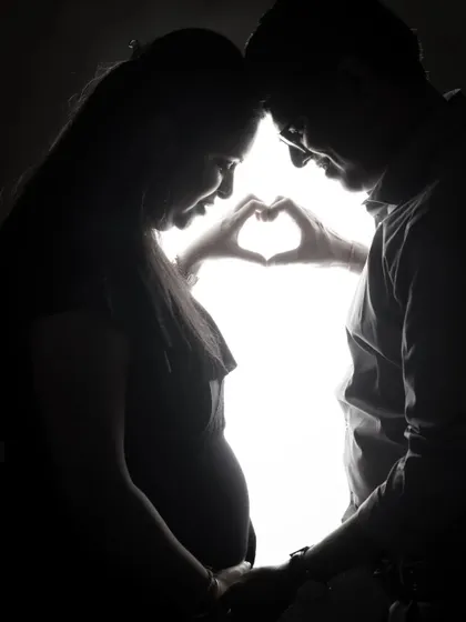 A tender silhouette of an expecting couple. The backlighting creates a beautiful halo effect, emphasizing their connection and the shape of the baby bump.