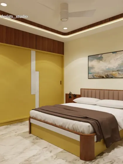 A full view of the mustard-yellow bedroom, showing how the warm tones are carried through the bed frame and side tables. The marble-patterned floor and simple white walls balance the strong color, keeping the room bright.