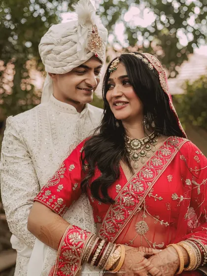 A close, intimate portrait capturing the bride's joyful smile and the groom's loving gaze. The intricate details of their wedding attire are beautifully highlighted.