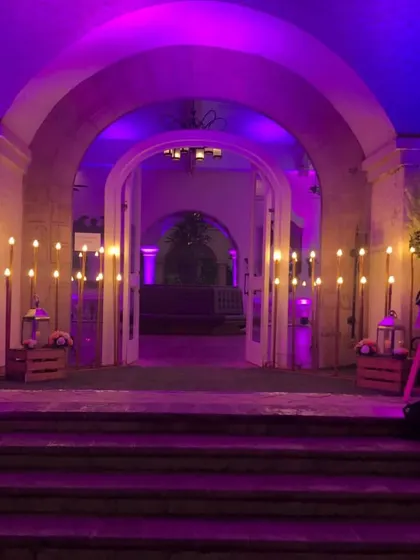 Here is the same entranceway illuminated with bold purple lighting. This shows how we use color to completely change the venue's atmosphere to match your event's theme, perfect for a cocktail party or sangeet.