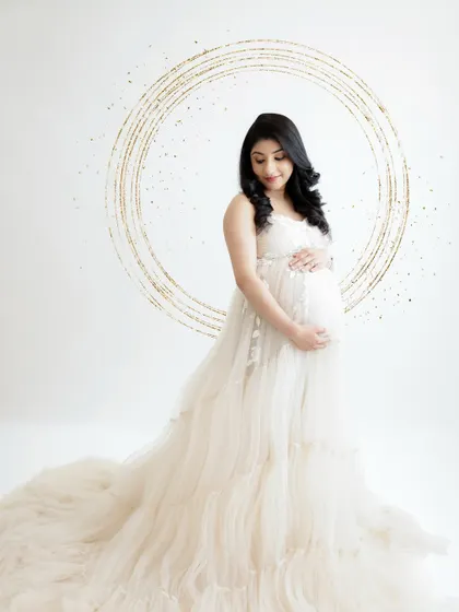 A magical and artistic portrait. The mom-to-be is framed by a golden, sparkling circle, her white gown adding to the ethereal feel.