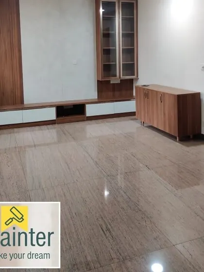 A spacious, empty living room with freshly painted white walls and a wooden media center, ready for the residents to move in.