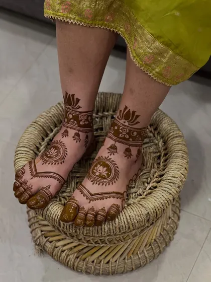 A simple yet beautiful foot design with a central lotus mandala and bell motifs, perfect for a minimalist bride.