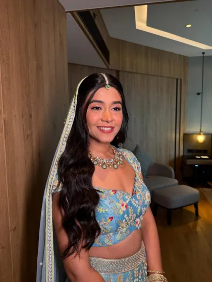 A modern and fresh half-updo with long, flowing waves. The look is completed with a delicate floral hairpiece, perfect for a daytime wedding or Mehendi.