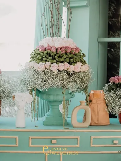 A beautiful display of tiered floral arrangements on a mint-green console table. The mix of pinks, whites, and greens creates a fresh and romantic color palette.