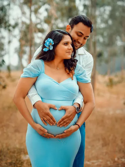 A sweet and romantic pose for an outdoor couple's maternity shoot. Making a heart shape on the baby bump is a classic for a reason.