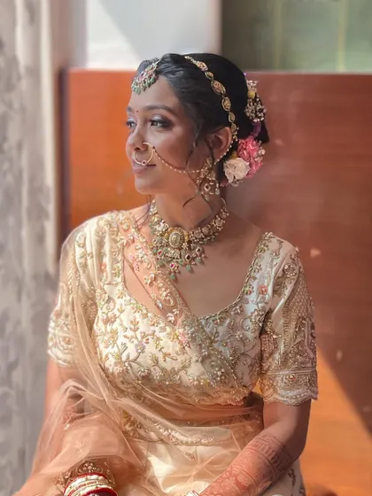 A beautiful shot of the bride in a golden-ivory lehenga, bathed in natural light. The makeup is soft and glowing.