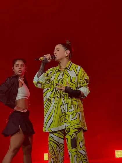 A live performance against a bold red backdrop. The lighting and stage design are just as important as the artist to create a visually stunning entertainment experience.