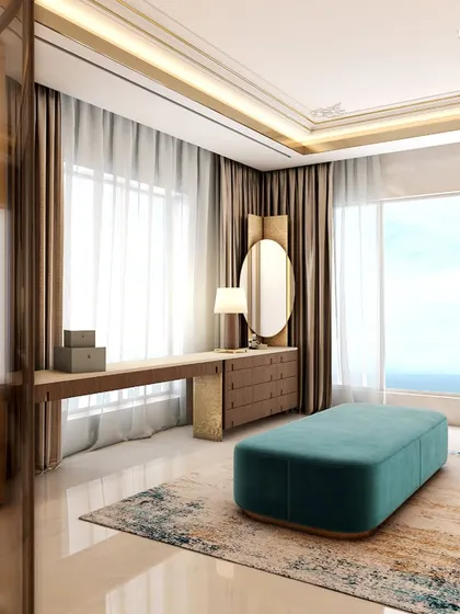 A view from the master suite into the luxurious bathroom and dressing area. The space is designed for openness, with large windows providing natural light and a sea view, while a teal ottoman adds a pop of color to the neutral palette.