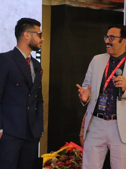 A candid moment on stage at the Excellence Iconic Awards, sharing a laugh with the host.
