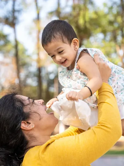 The pure delight of being lifted high. This candid photo of a mother and her daughter captures a moment of playful interaction and laughter. These are the lively, action filled shots that truly show the bond you share before they grow too big to fly.