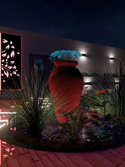A night view of a terrace designed for ambiance. The space is defined by its lighting, from the glowing central urn and floor-integrated LEDs to the backlit decorative tree panel that serves as a stunning focal point.