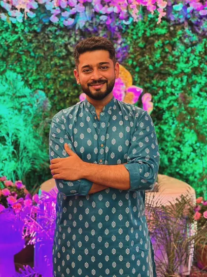 Posing in a teal-blue printed kurta during a festive event. The vibrant setting and confident posture make this suitable for showcasing festive wear collections.