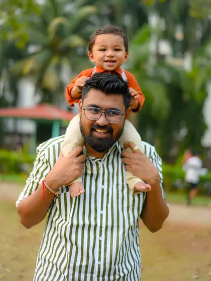 A classic father-son photo. The joy is evident as the son gets a piggyback ride on his dad's shoulders during our park photoshoot.