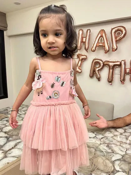 We had so much fun designing this pink tiered tulle dress for a special second birthday. The bodice is adorned with cute, handcrafted embellishments like little dolls and butterflies for a playful touch.