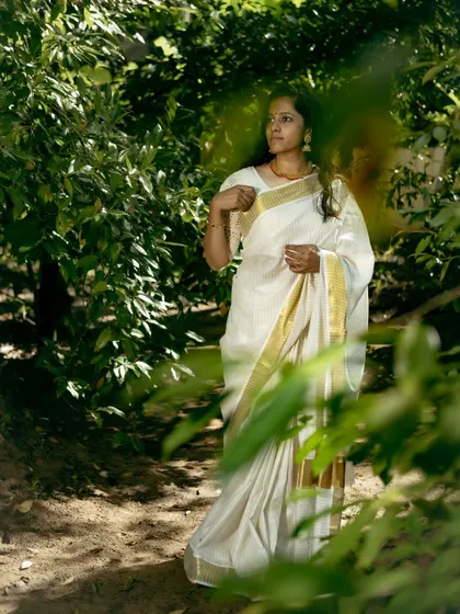 A candid shot of me in a Kerala saree amidst lush greenery, capturing the natural beauty and serene vibe of Onam.
