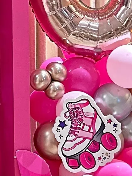 A roller skate prop and a large foil number balloon as part of a retro or Barbie-themed party decoration.