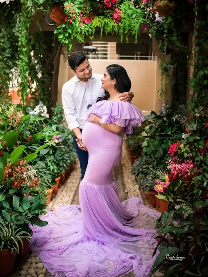 Looking at each other with so much love, this couple is surrounded by the vibrant life of a garden, mirroring the new life they are about to welcome.