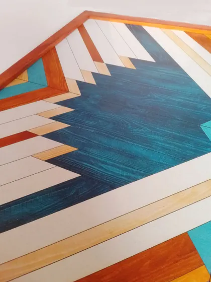 A detailed close-up of our geometric blue wood art. You can see the beautiful wood grain through the teal stain, adding an organic element to the sharp, Aztec-style pattern.