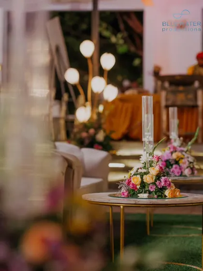 A view of the reception decor, with the warm glow of the floral lamps in the background.