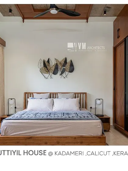 A bedroom in Kuttiyil House with a custom wooden wardrobe, a leaf-motif wall art piece, and a window looking out onto a private courtyard.