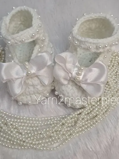 These white booties feature a large satin bow and are detailed with pearls along the strap and bow center, creating a very formal and elegant look.