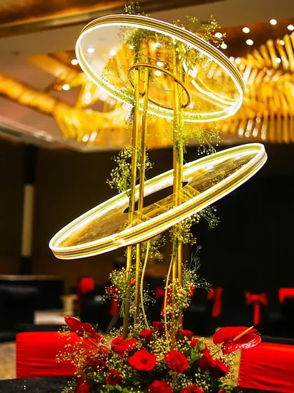 A modern, illuminated centerpiece designed for a 60th birthday celebration. The glowing rings and red roses perfectly capture the event's stylish red and black theme.