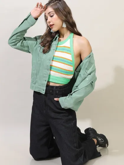 A layered look combining a striped halter top with a green denim jacket and wide-leg jeans, creating a stylish and textured outfit.