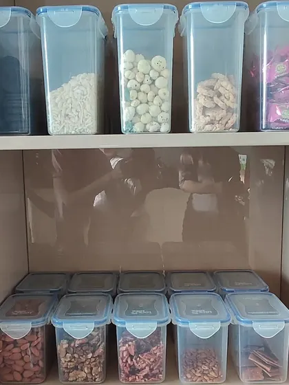 A well-organized snack pantry using airtight, clear containers. Dry fruits and other snacks are stored in uniform boxes, making it easy to see what's inside and when it's time to restock.