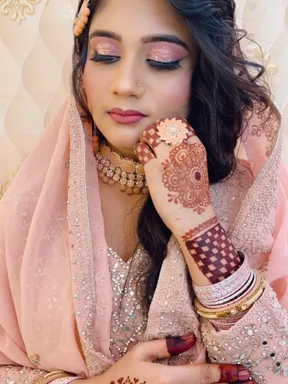 A detailed shot focusing on the soft pink eye makeup and the beautiful henna design, essential parts of the bridal look.