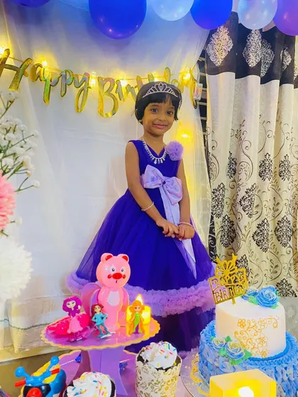 The birthday girl posing by her cake in her custom blue and lilac gown.