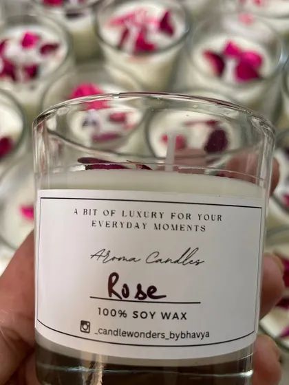 Holding up one of the finished rose votive candles, showing the custom label and beautiful floral details.
