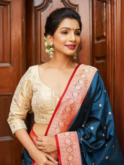 A model pairs a classic cream brocade blouse with statement pearl and kundan style earrings, creating a timeless and sophisticated look.