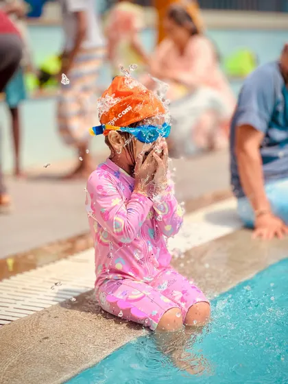 A series of candid shots showing a young swimmer's journey of getting comfortable at the pool's edge. From happy claps to playful splashes, it's all part of the learning process.